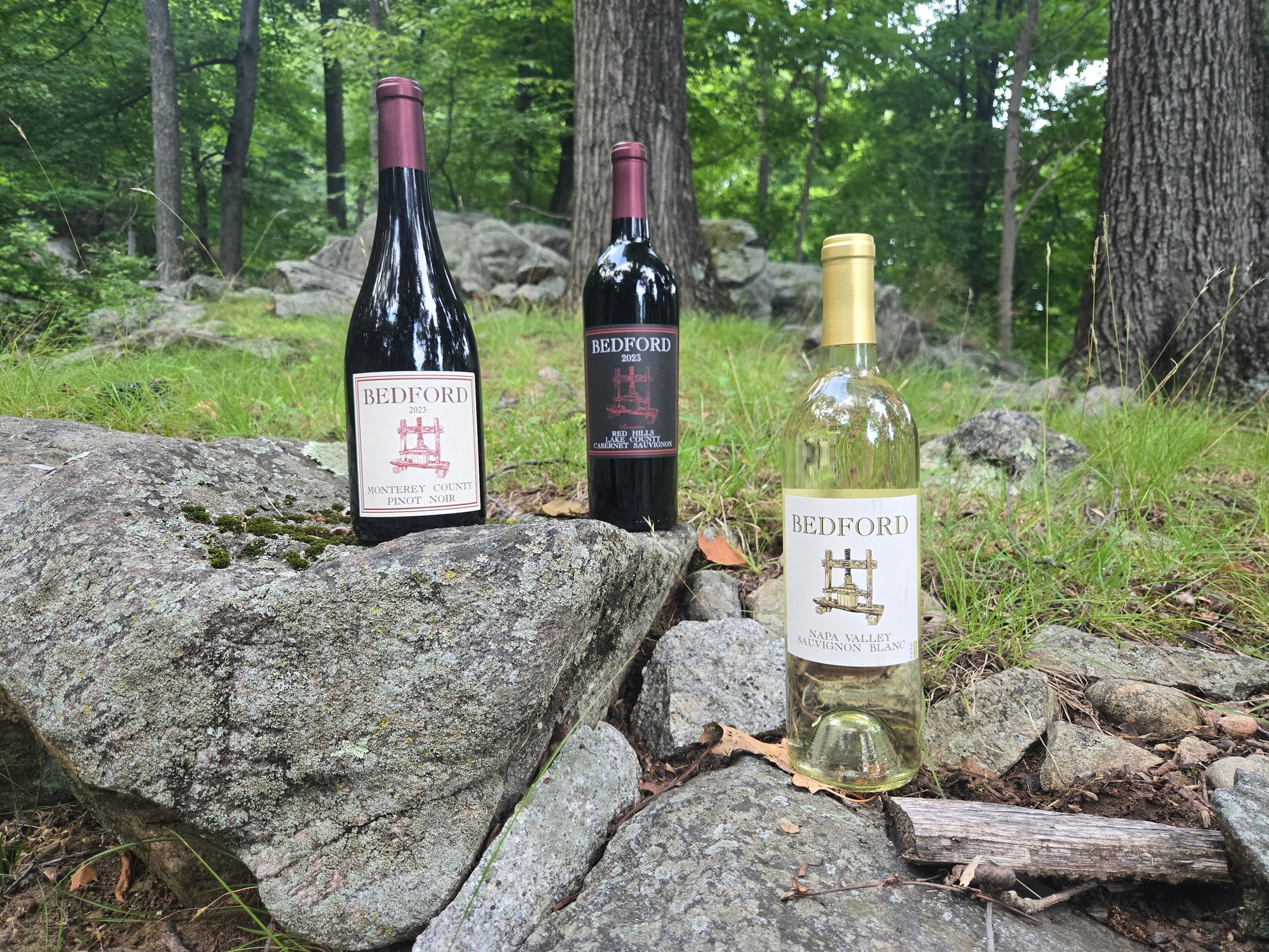 Three Bedford wines staged on rocks in the woods
